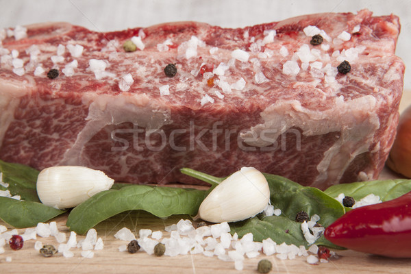 Close-up piece of fresh marbled beef, chili pepper, parsley, onion, garlic, ribs lie on a wooden tra Stock photo © mcherevan