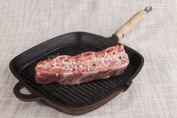 Close-up piece of fresh marbled beef with sea salt and black pepper,  on a cast-iron grill pan Stock photo © mcherevan