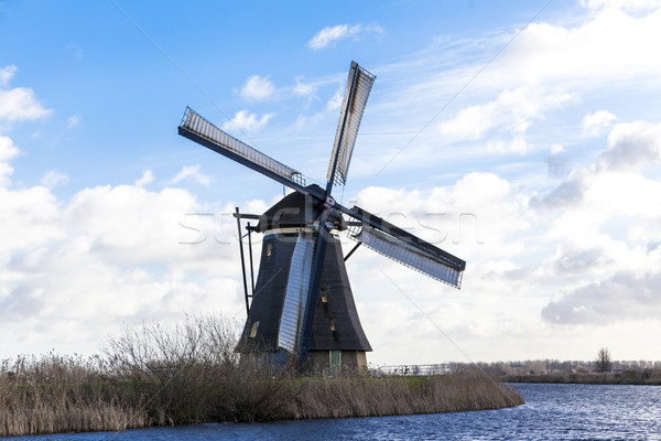 Old, traditional windmill in the Dutch canals. Netherlands.White clouds on a blue sky, the wind is b Stock photo © mcherevan
