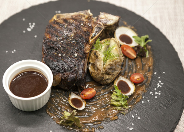 Ribeye steak from marble beef meat with vegetables and barbecue sauce. Served on a plate of black st Stock photo © mcherevan