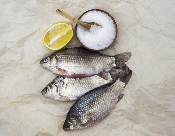 A  fresh carp live fish lying on a on paper background with a knife and slices of lemon and with sal Stock photo © mcherevan