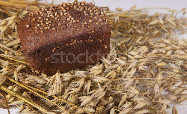 Loaf of homemade bread with black mustard seeds on table with rye spikelets  and oats Stock photo © mcherevan