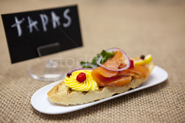 TAPAS poster . Fresh Spanish tapas on bread baguette smoked Norwegian salmon with black olive butter Stock photo © mcherevan