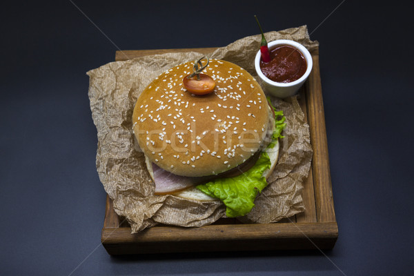 Classical American fresh juicy burger with chicken and ham on a wooden tray with a spicy chili sauce Stock photo © mcherevan