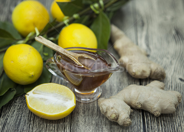 The composition of glass vase with floral honey and wooden spoon with lemon and ginger on a wooden b Stock photo © mcherevan