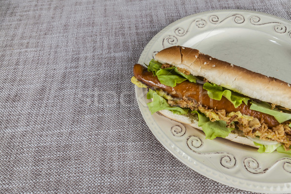 Fresh tasty hot dog with fried onions and fresh lettuce with mustard on a porcelain plate Stock photo © mcherevan