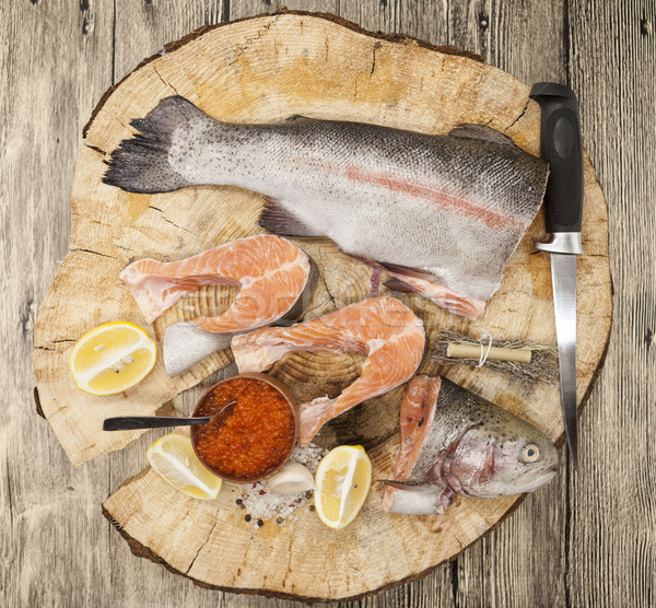 Fresh Norwegian rainbow trout with lemon red caviar, sea salt, knife and onions on a wooden backgrou Stock photo © mcherevan