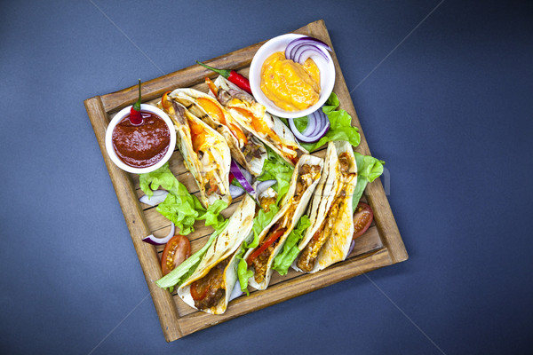 Mexican Tortilla with meat, beef and stewed vegetables and spicy sauce on a wooden tray. Stock photo © mcherevan