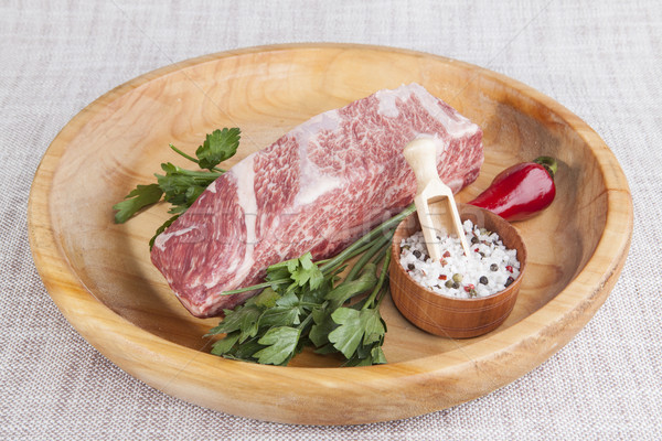 A piece of fresh marbled beef, chili pepper, parsley, onion, garlic, ribs lie on a wooden tray Stock photo © mcherevan