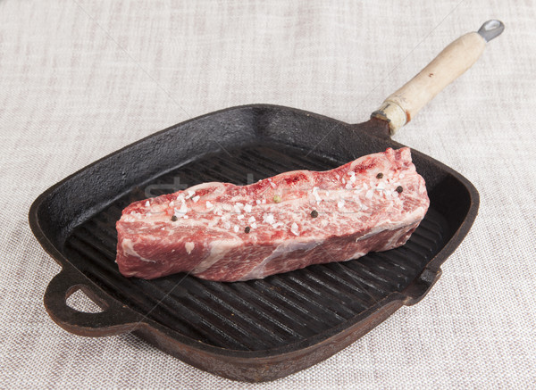 Close-up piece of fresh marbled beef with sea salt and black pepper,  on a cast-iron grill pan Stock photo © mcherevan