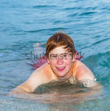 teenage boy enjoys swimming in the ocean and laughes Stock photo © meinzahn