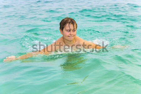 teenage boy swims in the ocean and has saltwater in the eyes  Stock photo © meinzahn