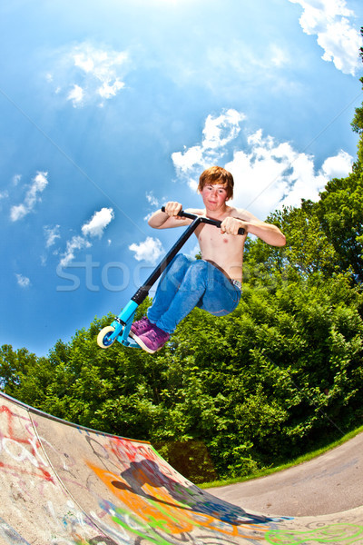 Stock photo: young boy going airborne with a scooter