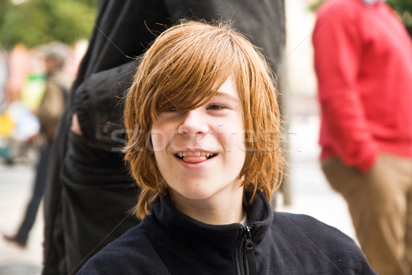 boy with long red hair pokes his tongue as a joke  and smiles Stock photo © meinzahn