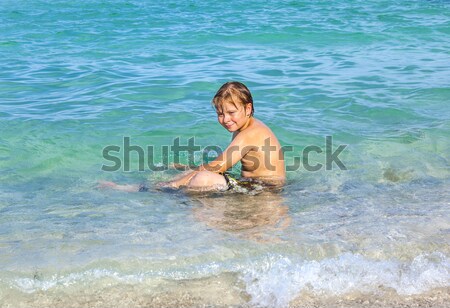 boy is swimming on his surfboard and happily smiling in  a beaut Stock photo © meinzahn