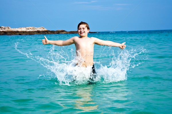 boy is enjoying the clear warm water at the beautiful beach but  Stock photo © meinzahn