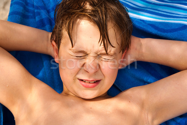 cute young boy at the beach closes eyes because of bright sunlig Stock photo © meinzahn