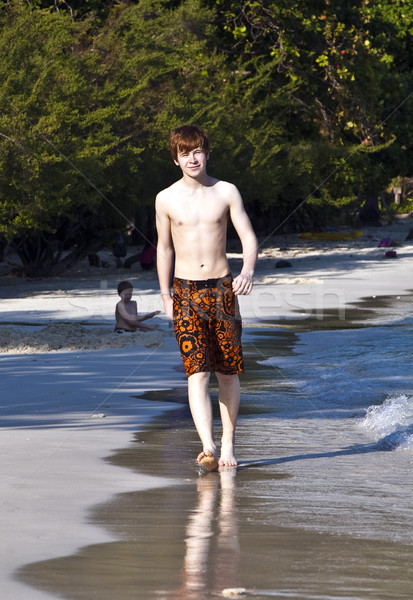 boy with red hair in bathing cloths is walking on a beautiful be Stock photo © meinzahn