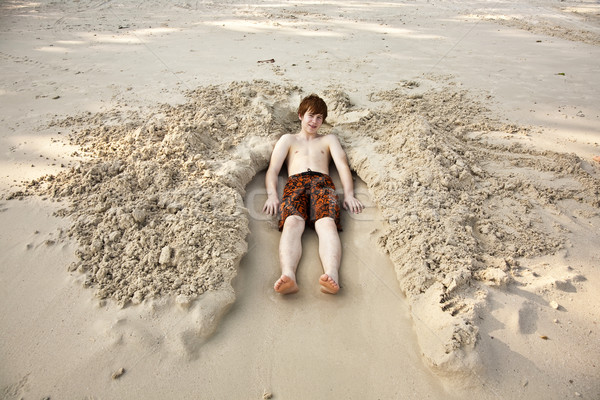 boy  is lying in a sandy bed at the beauti ful beach Stock photo © meinzahn