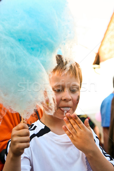 Stock photo: boy enjoys cotton candy at the fair and licks his hands 