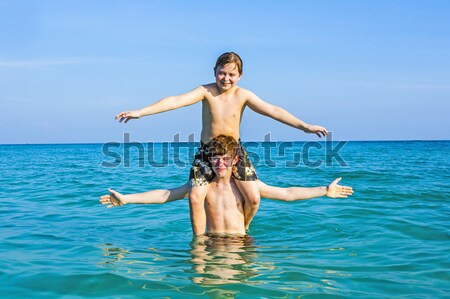 Stock photo: boy is surfing on a small surfboard in a beautiful sea with crys