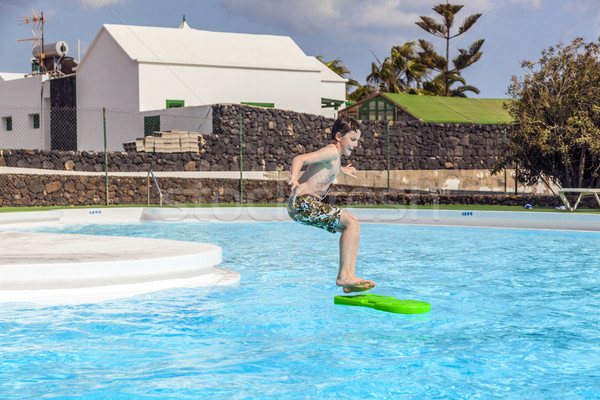 Menino saltando piscina prancha de surfe água cara Foto stock © meinzahn