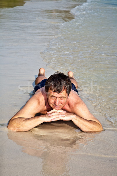 Man in bathingsuit is lying at the beach and enjoying the saltwa Stock photo © meinzahn