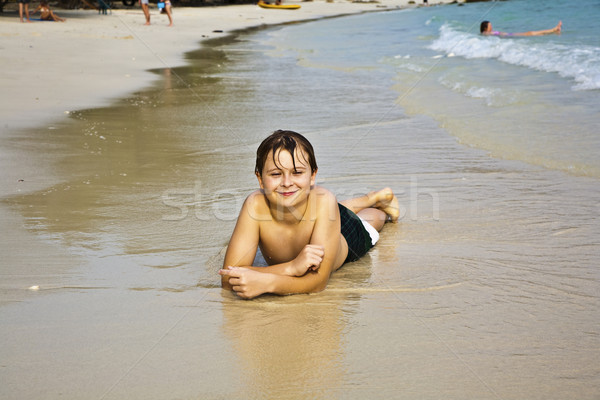 young boy is lying at the beach and enjoying the warmness of the Stock photo © meinzahn