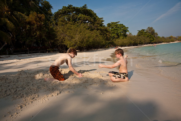 Stock photo: young boys are enjoying playing at the beach and building figure