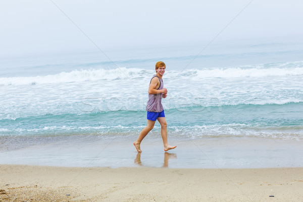 cute young teenage boy joging at the empty beach in the morning Stock photo © meinzahn