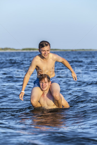  boys have fun playing piggyback in the ocean Stock photo © meinzahn