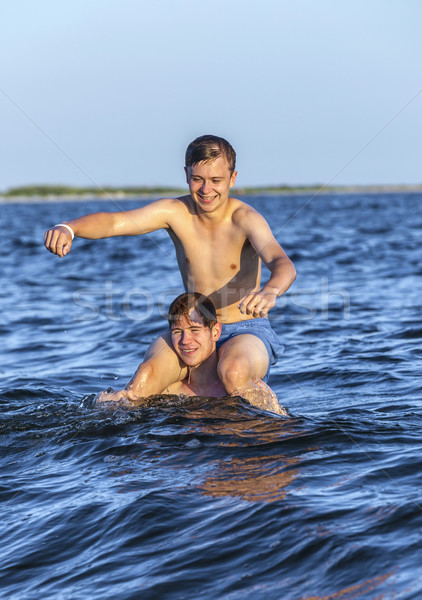  boys have fun playing piggyback in the ocean Stock photo © meinzahn