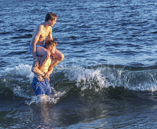  boys have fun playing piggyback in the ocean Stock photo © meinzahn
