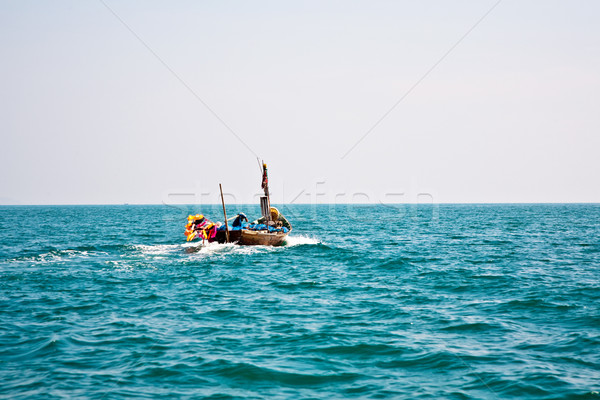 Stock photo: fisherman steers his small wooden boat out to the open sea 