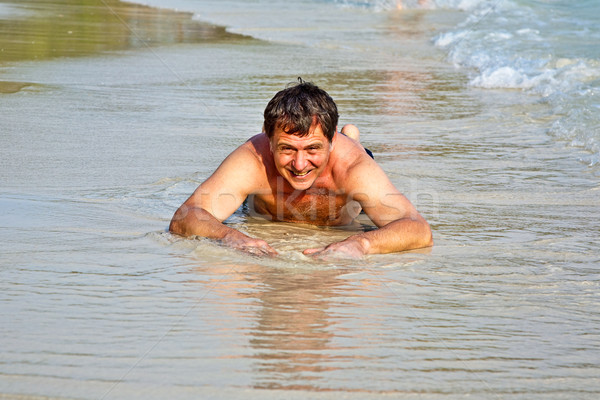 Man in bathingsuit is lying at the beach and enjoying the saltwa Stock photo © meinzahn