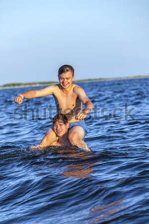 Stock photo:  boys have fun playing piggyback in the ocean