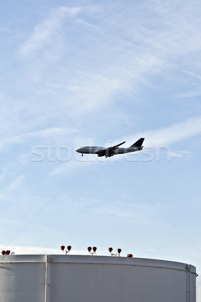 Stock photo: white tanks in tank farm with blue sky and approaching aircraft
