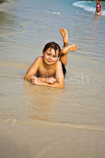 young boy is lying at the beach and enjoying the warmness of the Stock photo © meinzahn