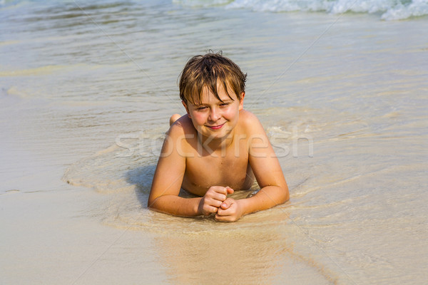 boy is lying at the beach and enjoys the water and looking self  Stock photo © meinzahn