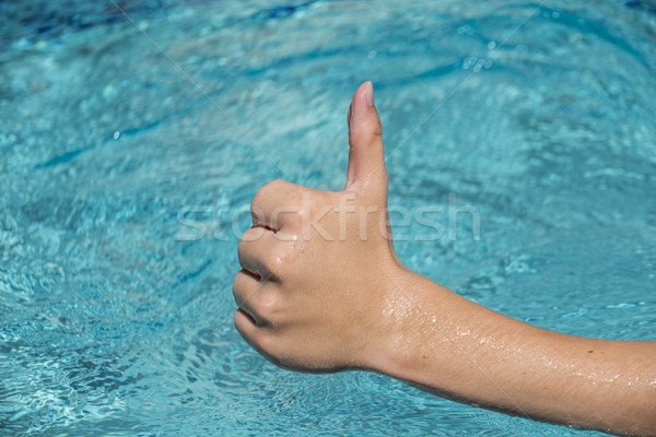 thumbs up sign of young man, teenager with blue water as backgro Stock photo © meinzahn