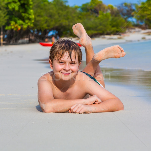 boy is lying at the beach and enjoying the warmness of the water and looking self confident and happ Stock photo © meinzahn