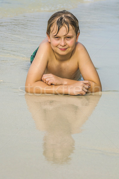 boy is lying at the beach and enjoying the warmness of the water Stock photo © meinzahn