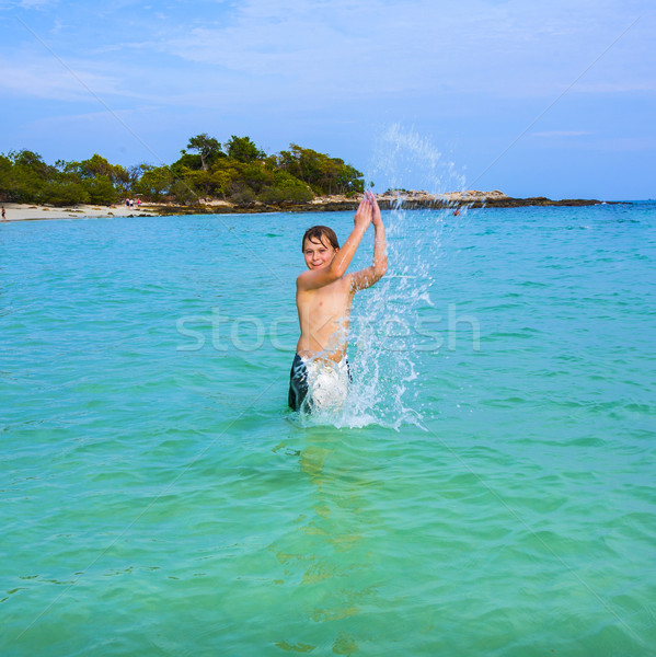 handsome boy enjoys sputtering with his hand in the tropical oce Stock photo © meinzahn