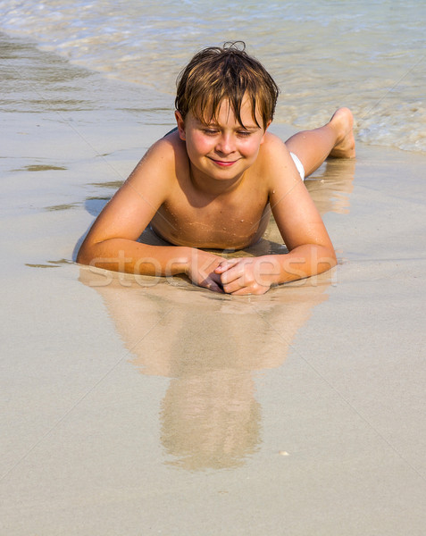 boy is lying at the beach and enjoys the water and looking self  Stock photo © meinzahn