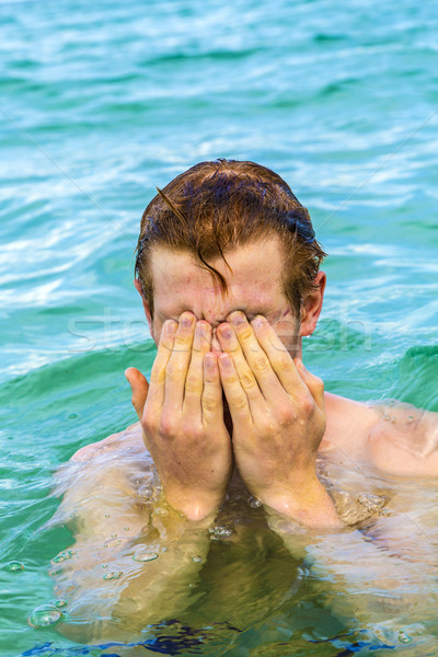 teenage boy cleans eyes of saltwater Stock photo © meinzahn