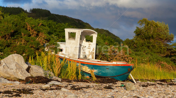 Small shipwreck at a loch with stone beach Stock photo © michaklootwijk
