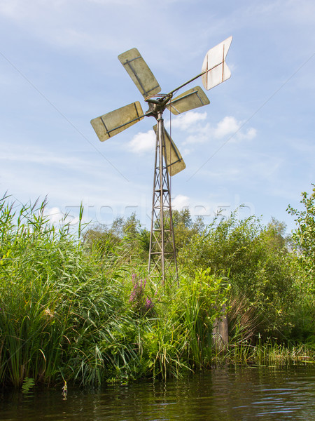 Small and rusted old metal windmill at the waterside Stock photo © michaklootwijk