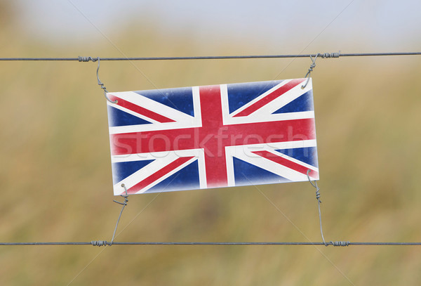 Border fence - Old plastic sign with a flag Stock photo © michaklootwijk