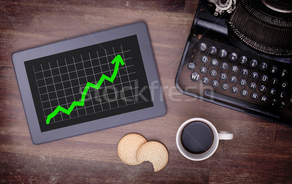 Stock photo: Tablet touch computer gadget on wooden table, graph positive