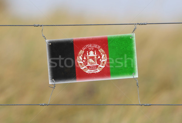 Border fence - Old plastic sign with a flag Stock photo © michaklootwijk